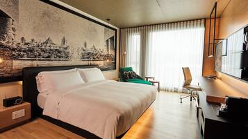 A hotel room with a large bed, a desk, a chair, and a television.