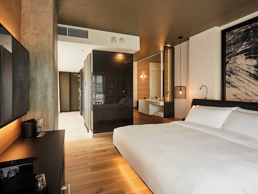 Een moderne hotelkamer met een groot bed, een flatscreen televisie, een koffieapparaat en een groot schilderij aan de muur.