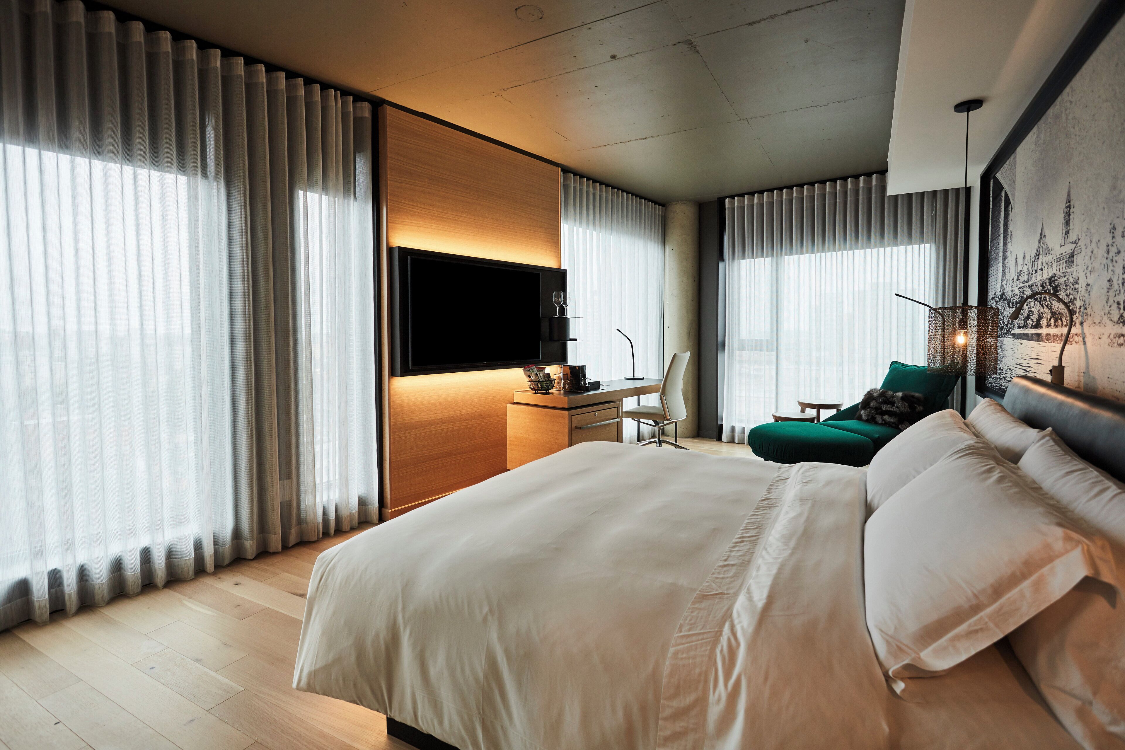 Ett modernt hotellrum med en stor säng, ett skrivbord med en platt-TV och en bekväm sittgrupp med en fåtölj och en soffa.