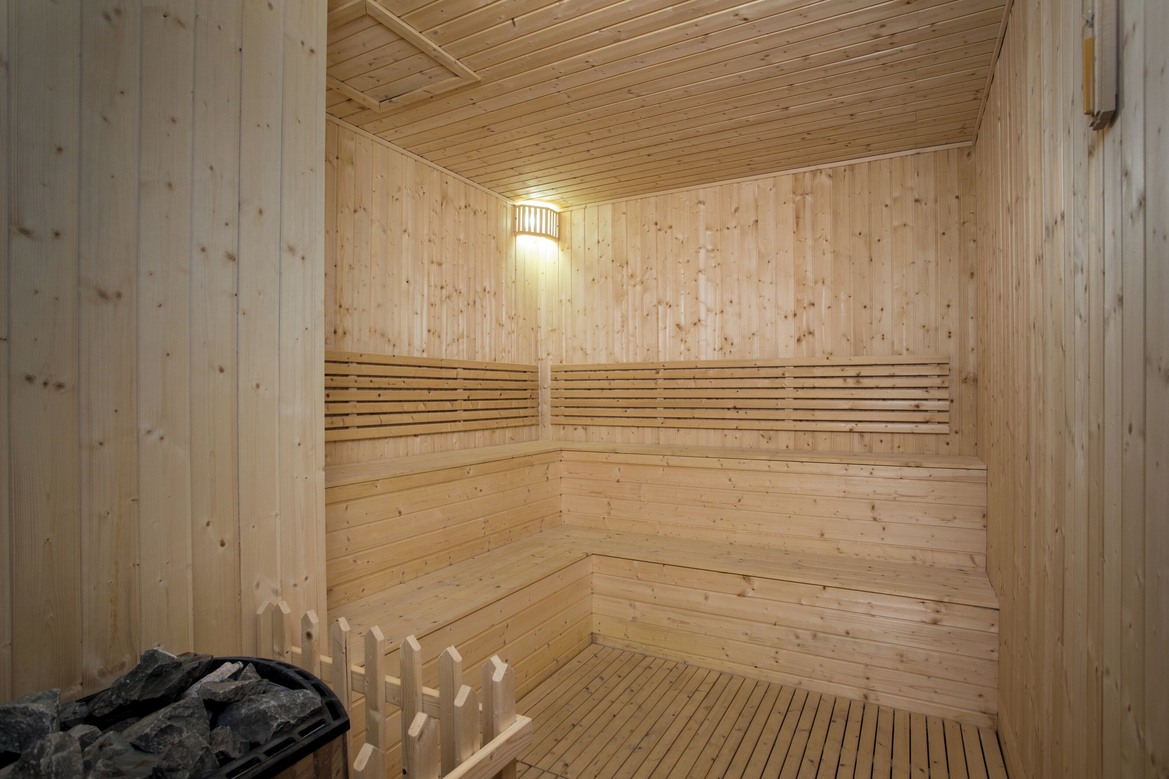 Una sauna de madera con bancos y una lámpara.