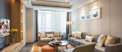 A modern living room with a sofa set, ottoman, and a flat-screen TV.