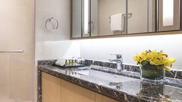 Un baño moderno con lavamanos de mármol, cabina de ducha de vidrio y un espejo grande.