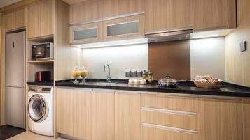 A modern kitchen with wooden cabinets, a built-in washing machine, and a black countertop.