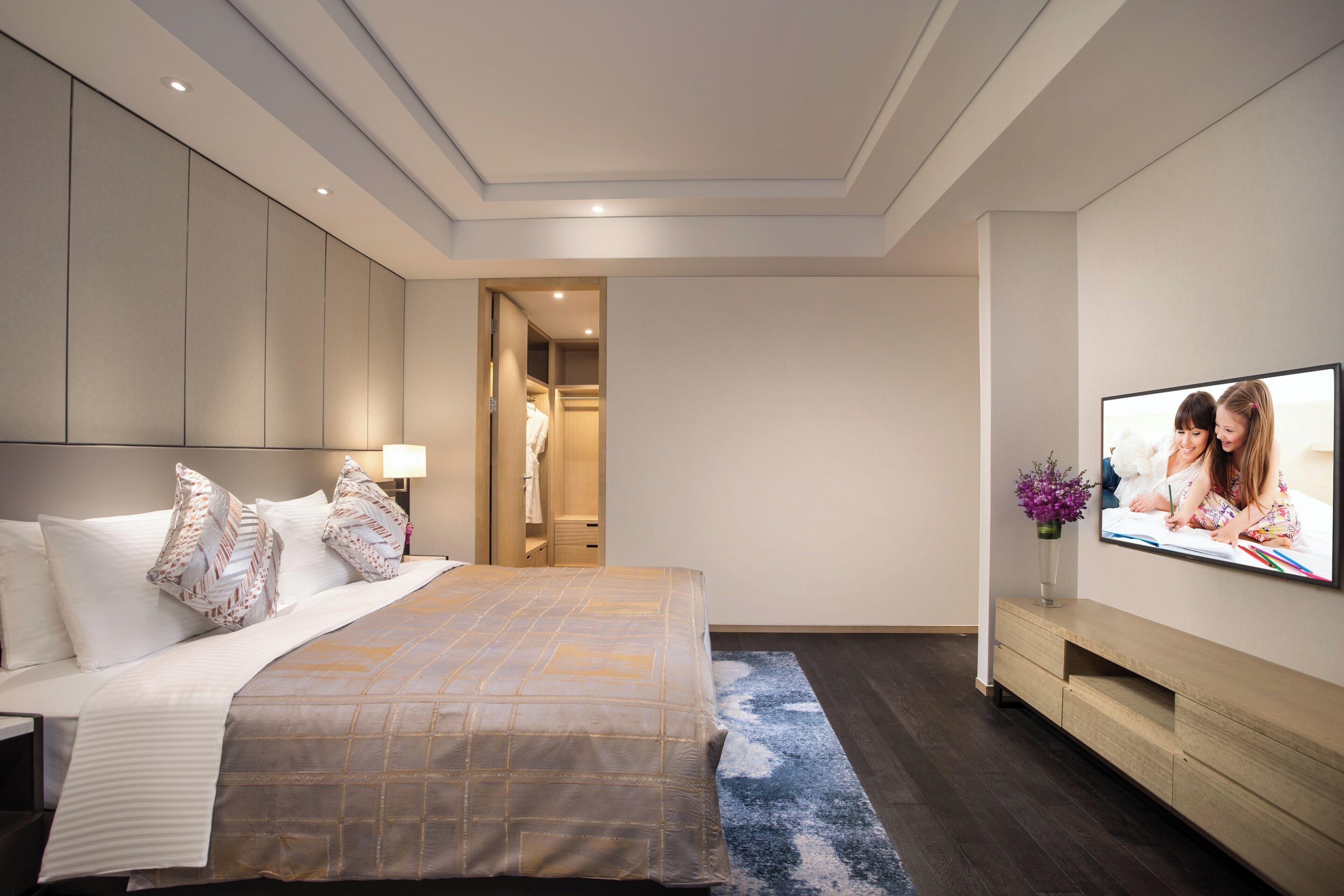 A modern hotel room with a large bed, a TV mounted on the wall, and a walk-in closet.