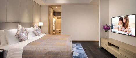 A modern hotel room with a large bed, a TV mounted on the wall, and a walk-in closet.