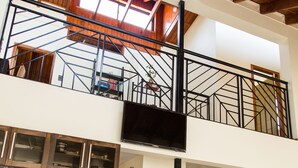 Une cuisine moderne dotée d’appareils électroménagers en acier inoxydable, d’une table à manger en verre et d’un escalier menant à un balcon.