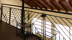 Un intérieur en bois avec un escalier, des rampes en métal et de grandes fenêtres qui laissent entrer la lumière naturelle.