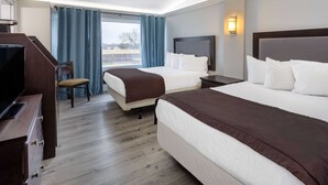 A hotel room with two beds, a desk, and a chair.