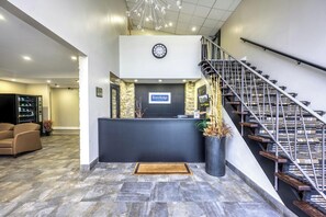 A reception area with a black counter, a clock, and a staircase with wooden steps.