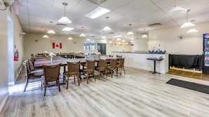 A spacious dining area with multiple tables and chairs, a kitchen area with a counter, and a fire extinguisher mounted on the wall.