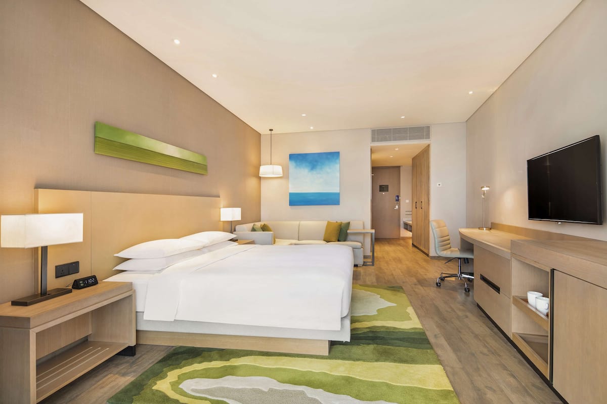 Een moderne hotelkamer met een groot bed, nachtkastjes, een flatscreen-tv en uitzicht op de oceaan.