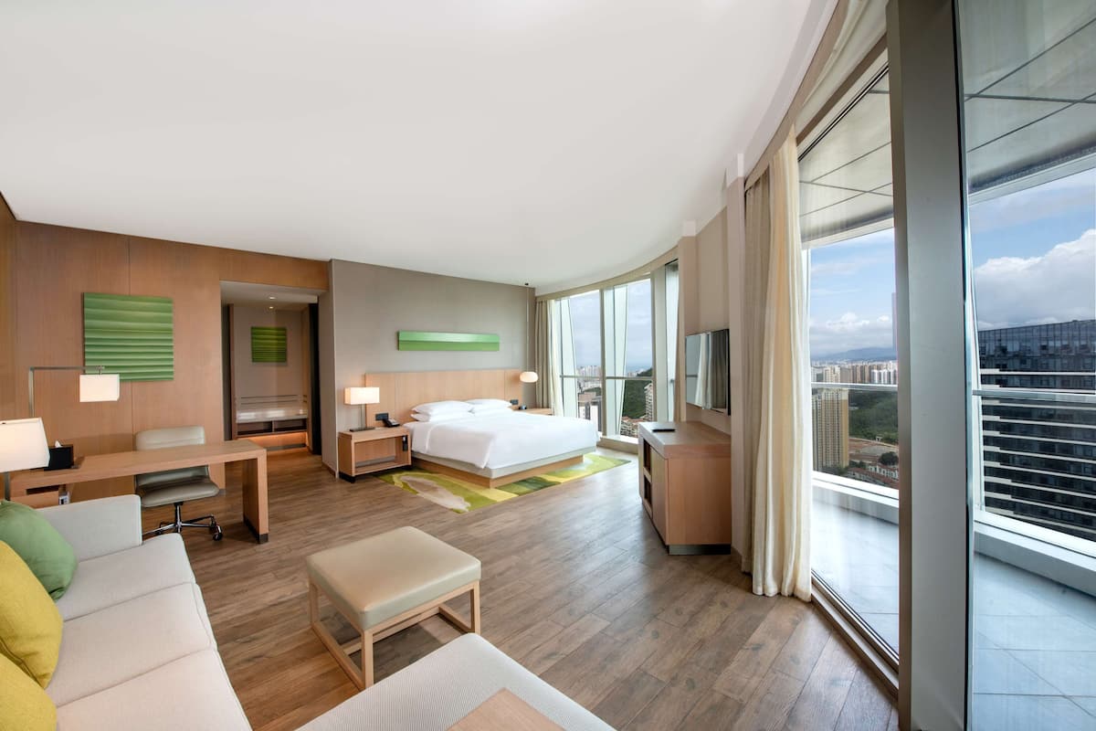 Een moderne hotelkamer met een groot bed, een bureau, een zithoek en uitzicht op de stad.