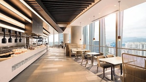 Un restaurant moderne doté d’un long comptoir, d’un espace salon et de grandes fenêtres offrant une vue sur la ville.
