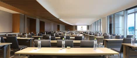 A conference room with multiple tables, chairs, and water bottles.