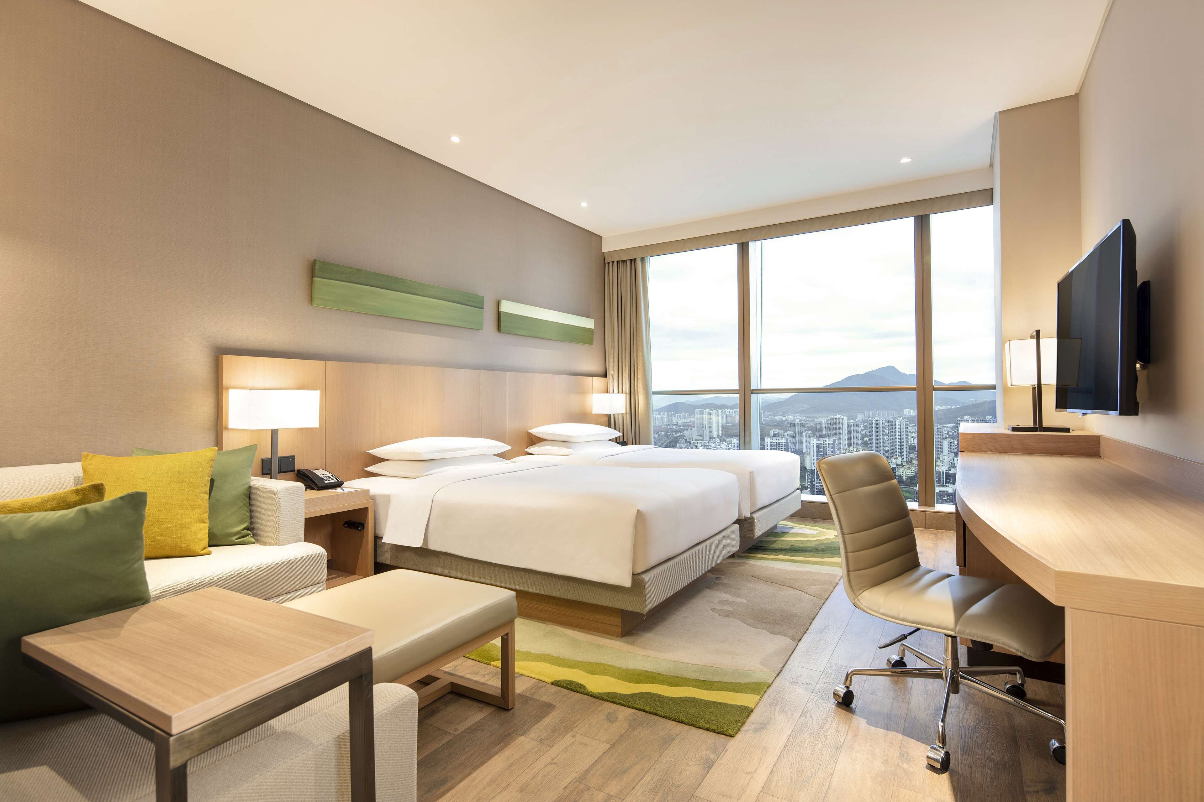Una habitación de hotel moderna con una cama grande, un escritorio, una silla, un sofá y un televisor.