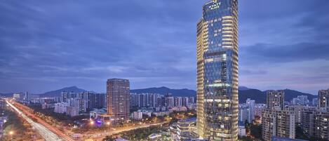 A high-rise hotel with a modern glass facade, surrounded by other buildings and a busy road.