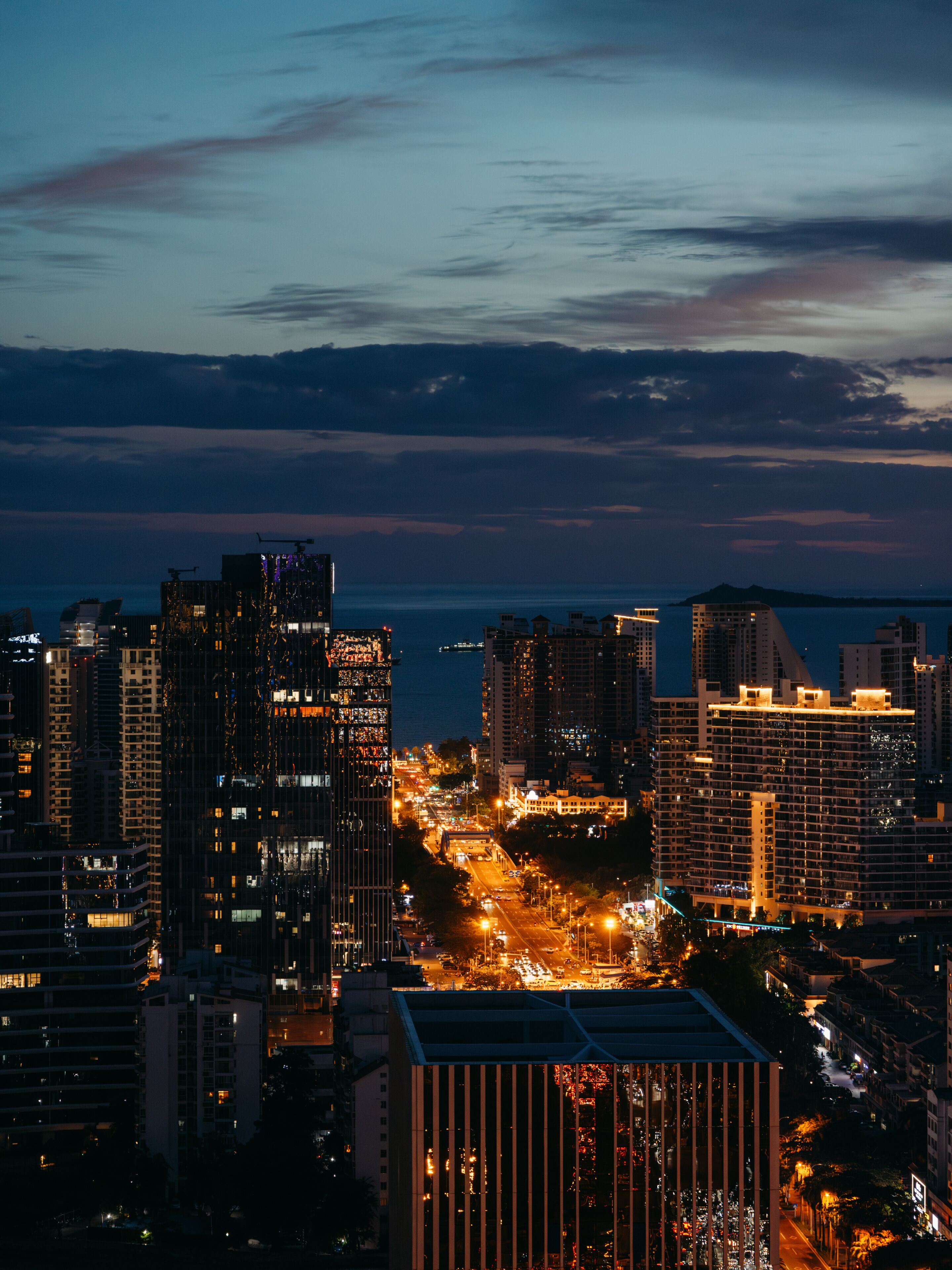 A nighttime cityscape with high-rise buildings and a view of the water.