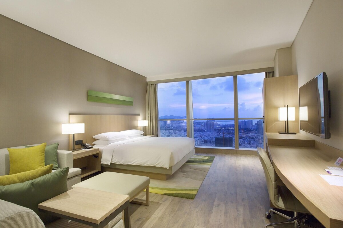 Een hotelkamer met een groot bed, een bureau, een stoel, een bank en een televisie.