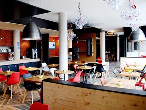 Un interior de restaurante moderno con techos altos, paredes de ladrillo visto y una mezcla de mobiliario de madera y metal.