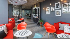 Een modern interieur met rode banken, een receptiebalie en ingelijste kunstwerken aan de muren.