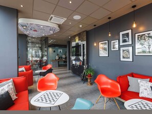 Un intérieur moderne avec des canapés rouges, un comptoir d’accueil et des œuvres d’art encadrées accrochées aux murs.