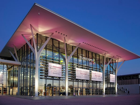 A modern building with large glass windows and a prominent sign reading "EUREXPO." - ibis Lyon Carré de Soie  (Vaulx-en-Velin)
