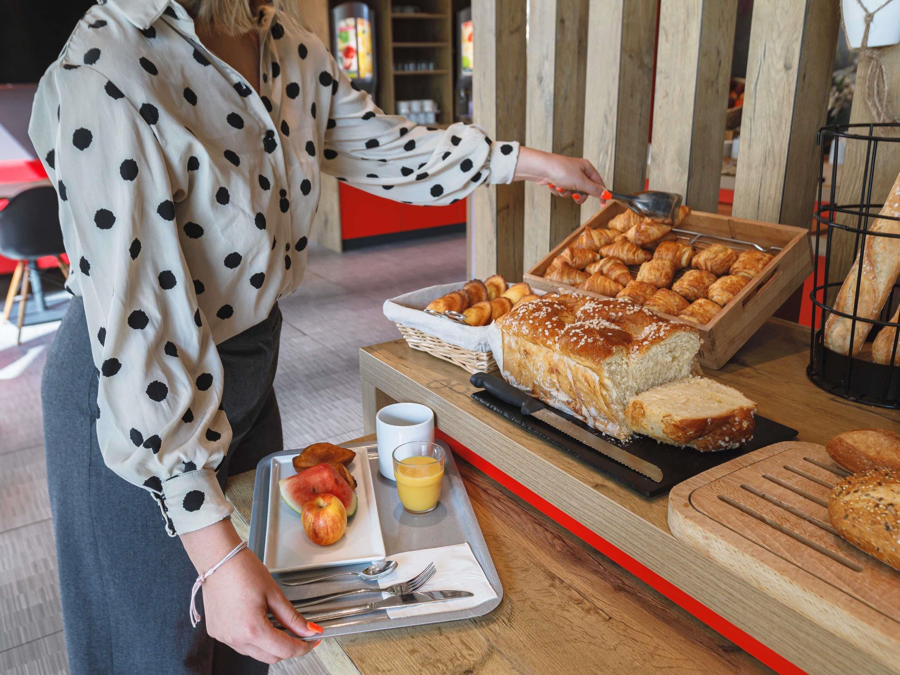 A buffet setup with various baked goods, a tray with fruits, and a beverage.