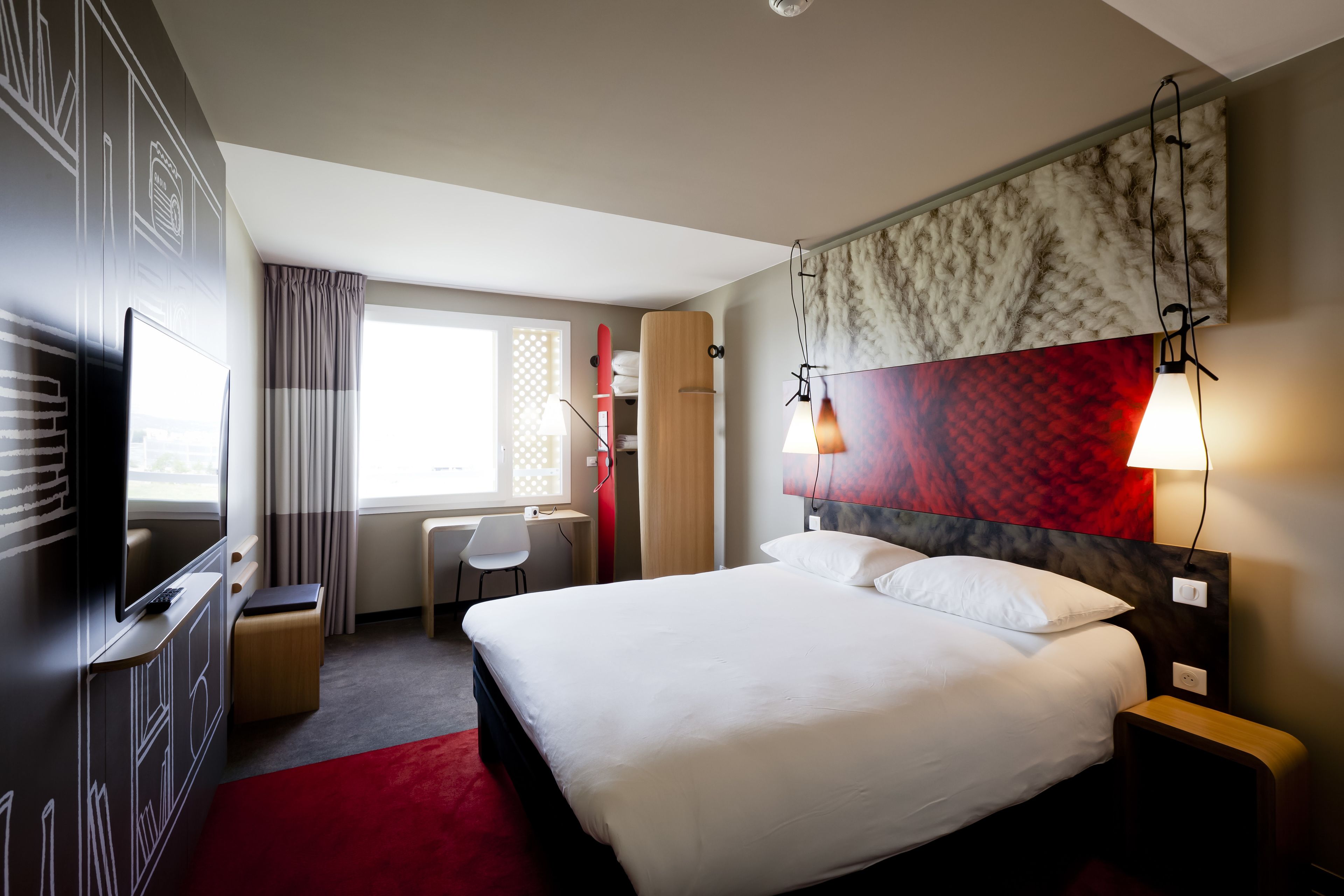 Een hotelkamer met een bed, bureau, stoel en televisie.