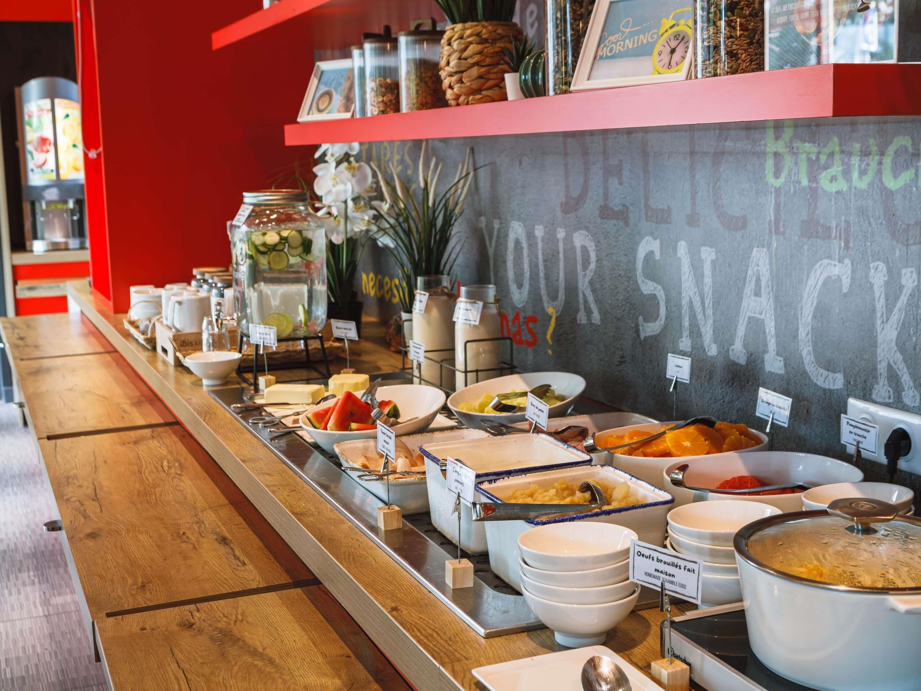 Ein Buffet mit verschiedenen Speisen und einem Schultafel-Schild, auf dem 'DELIGHT YOUR SNACK' steht.