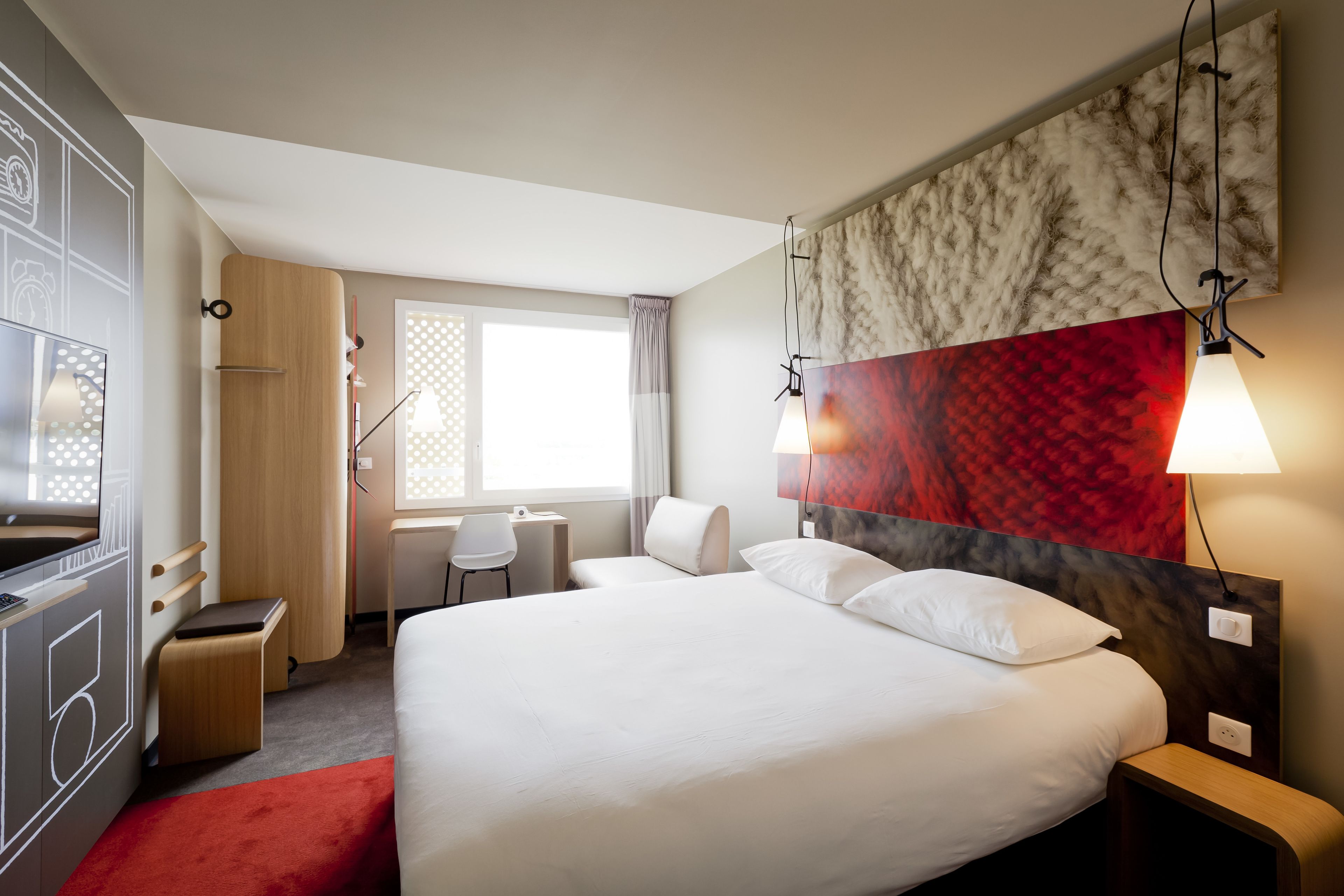 Une chambre d’hôtel avec un grand lit, un bureau, une chaise et un téléviseur.