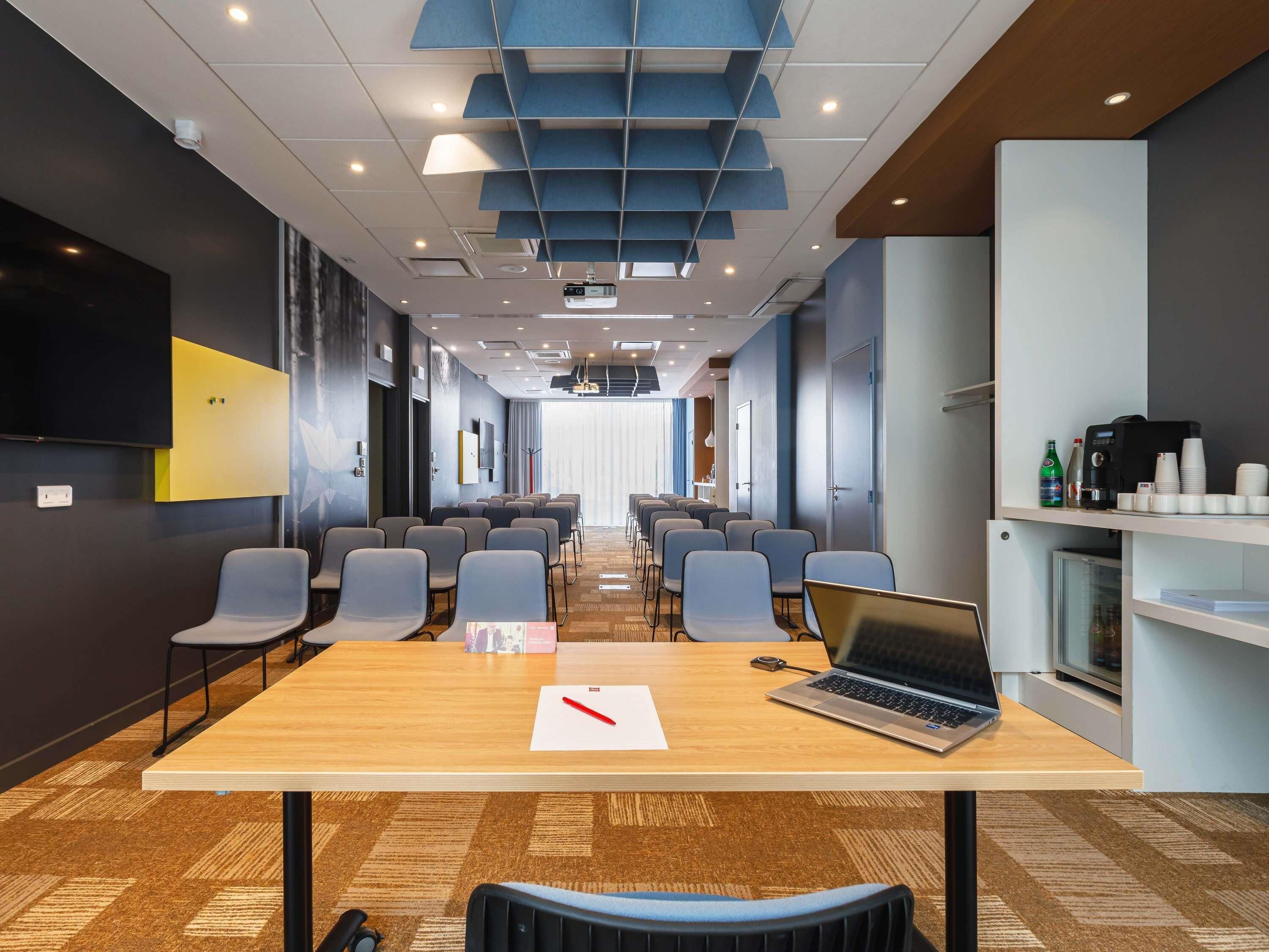 A conference room with a long table, chairs, a laptop, and a projector.