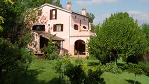 Une villa rose avec un jardin, un mur de pierre et un ciel d’un bleu éclatant.