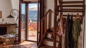 Une pièce rustique avec un escalier en bois, un balcon offrant une vue agréable et un coin repas comprenant une table et des chaises.