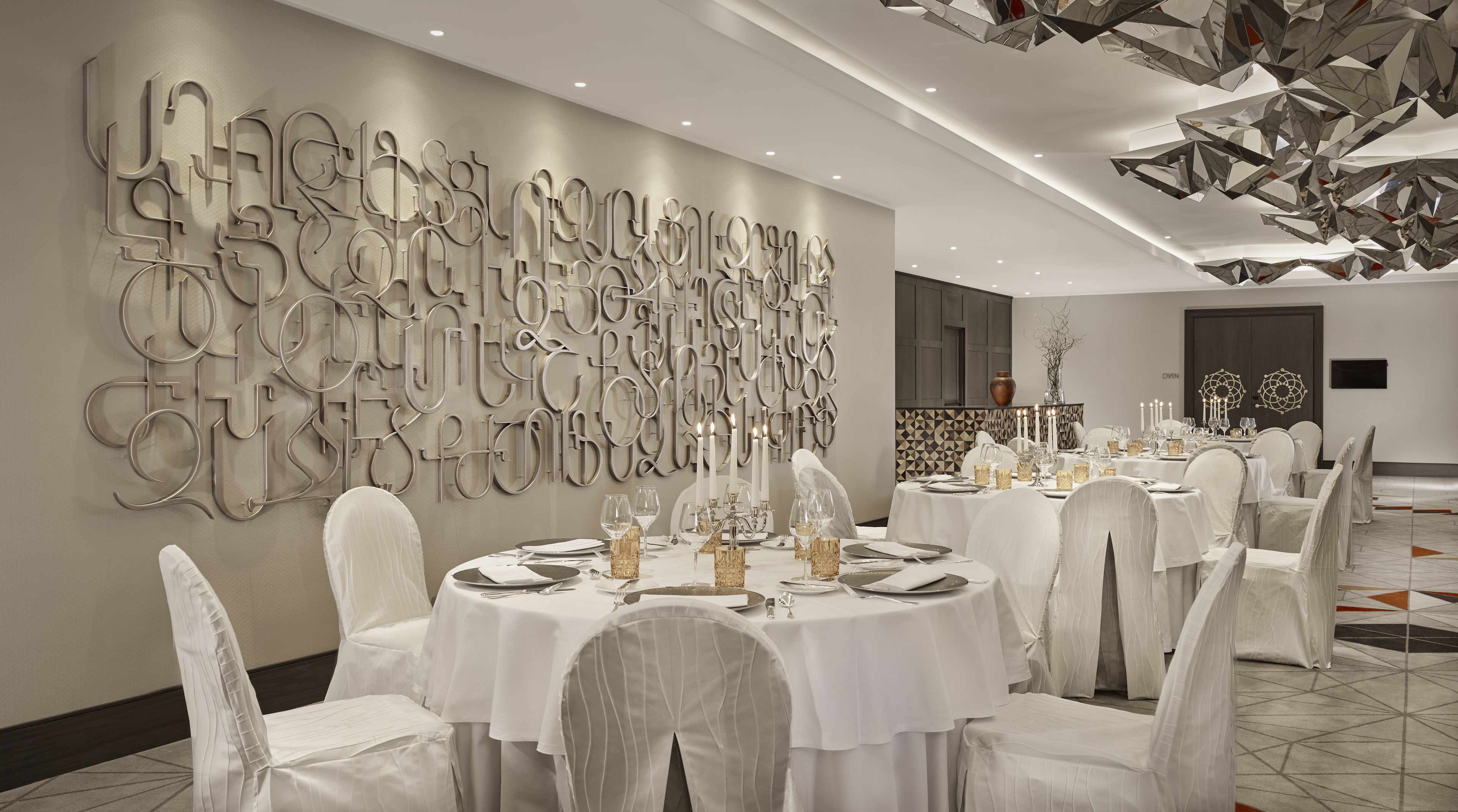 Un comedor elegante con mesas redondas, manteles blancos y sillas con fundas de gasa.