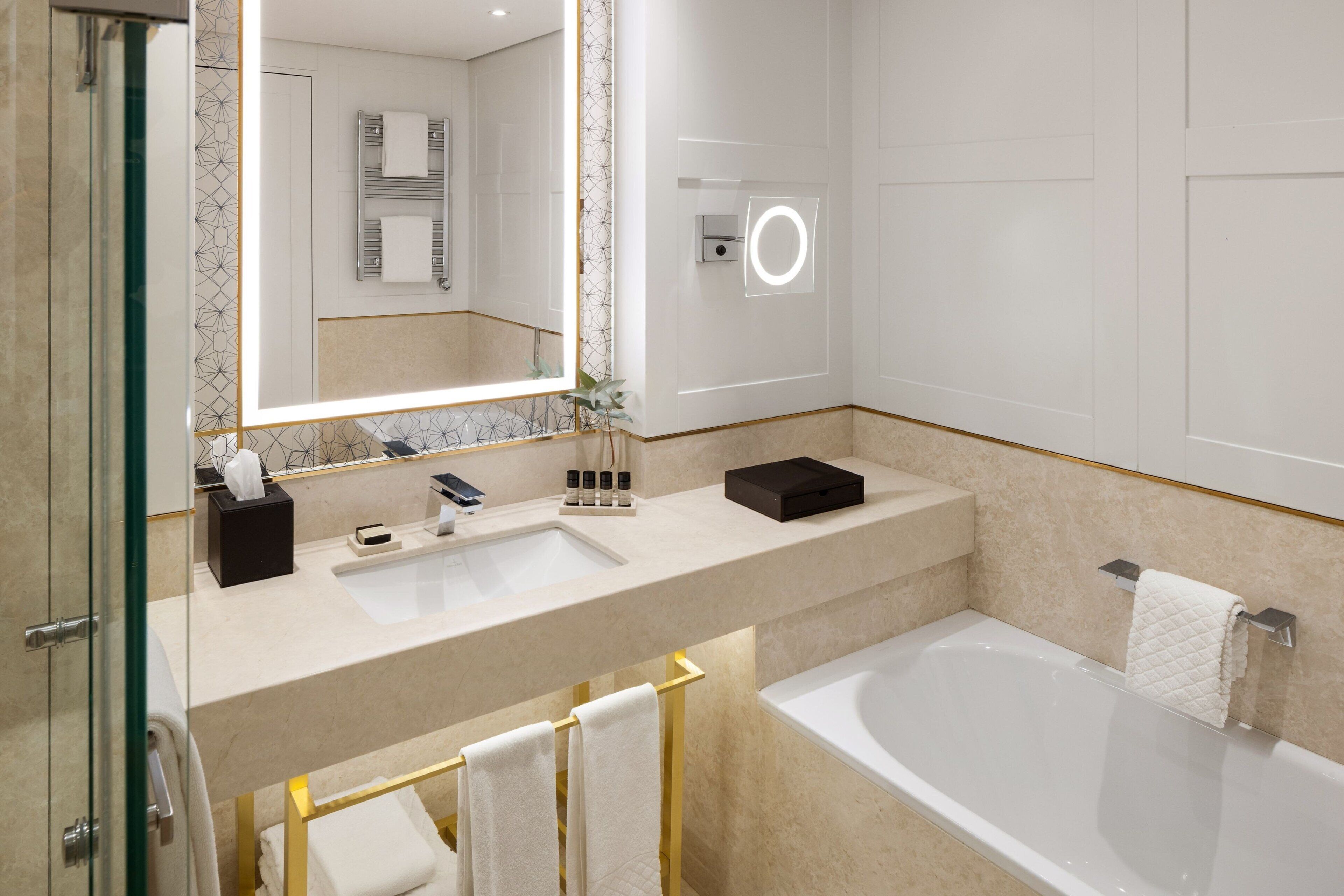 A modern bathroom with a glass-enclosed shower, a large mirror, a sink, and a bathtub.