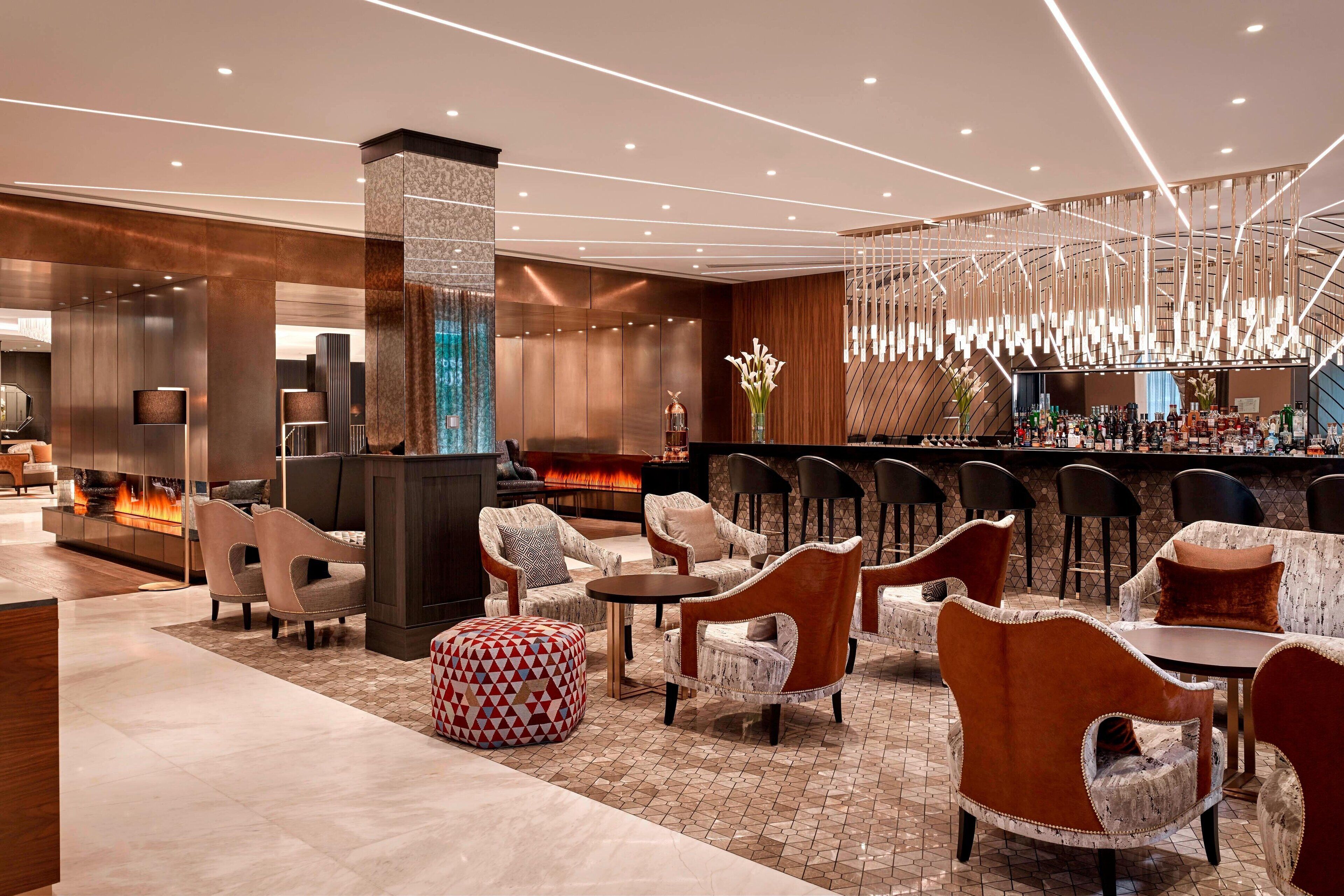 A modern lounge area with seating, a bar, and a fireplace.