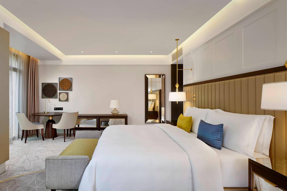 A hotel room with a large bed, bedside tables, a desk, and a chair.