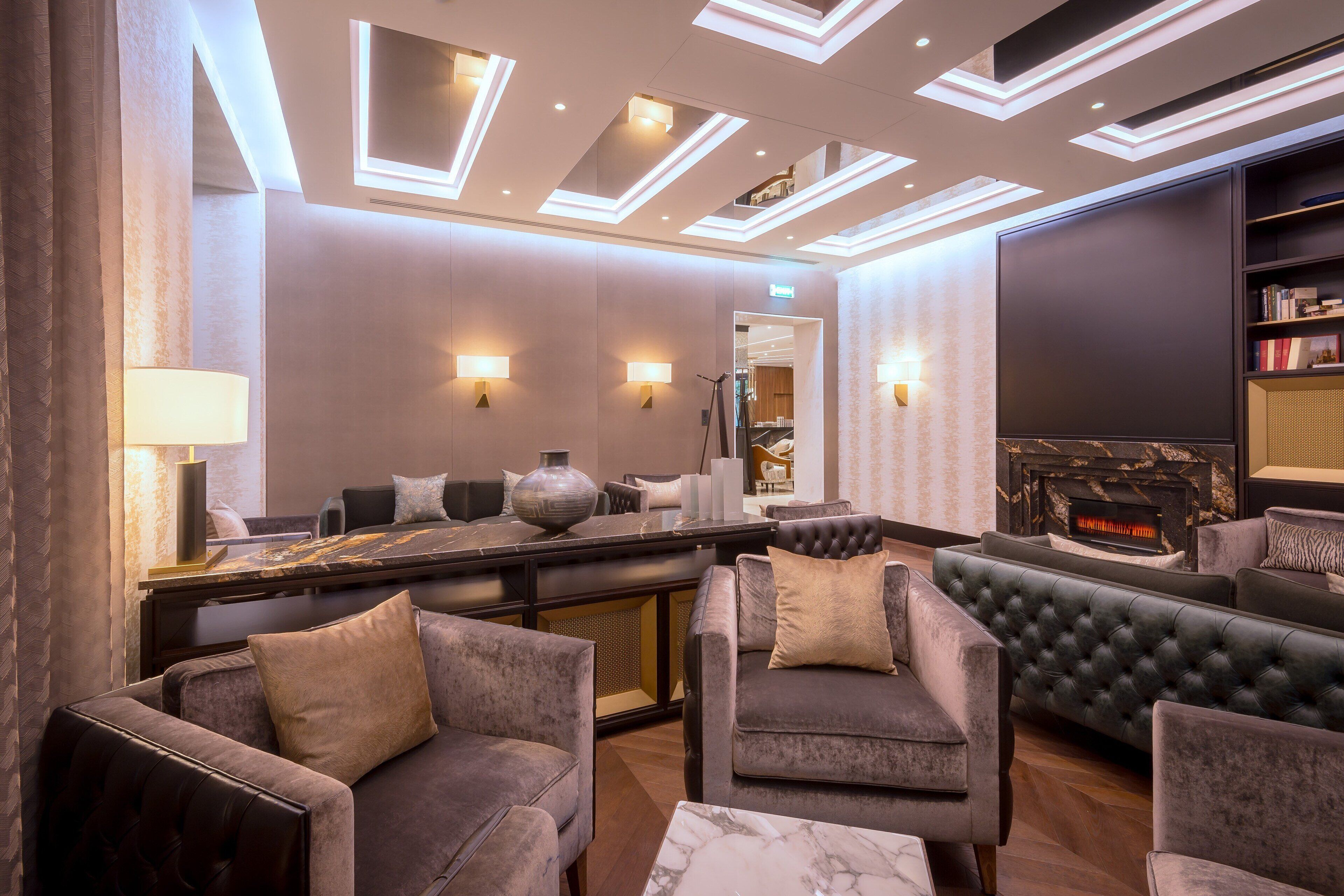 A modern lounge area with sofas, a fireplace, and a bar.