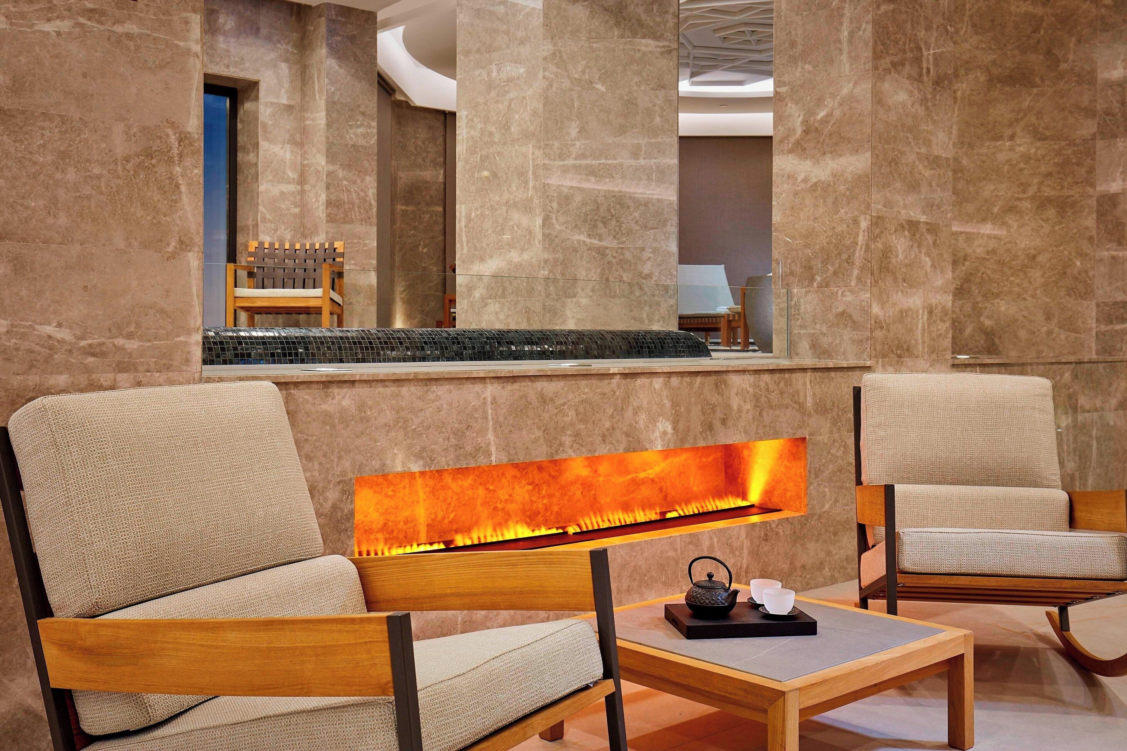 Eine moderne Lobby mit Kamin, zwei Sofas, einem Couchtisch und einem Holzstuhl.