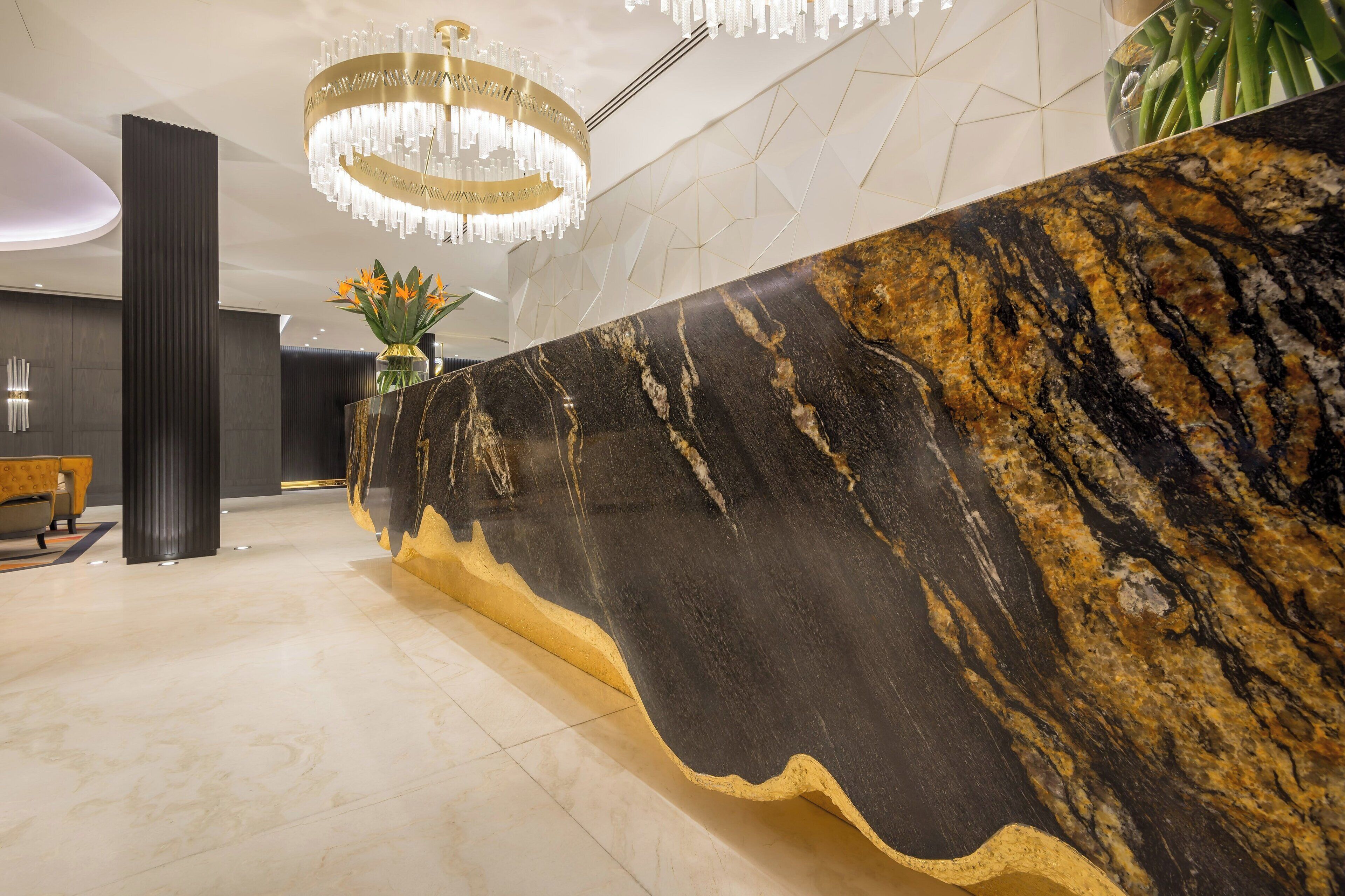A reception area with a marble counter, a chandelier, and a geometric wall pattern.