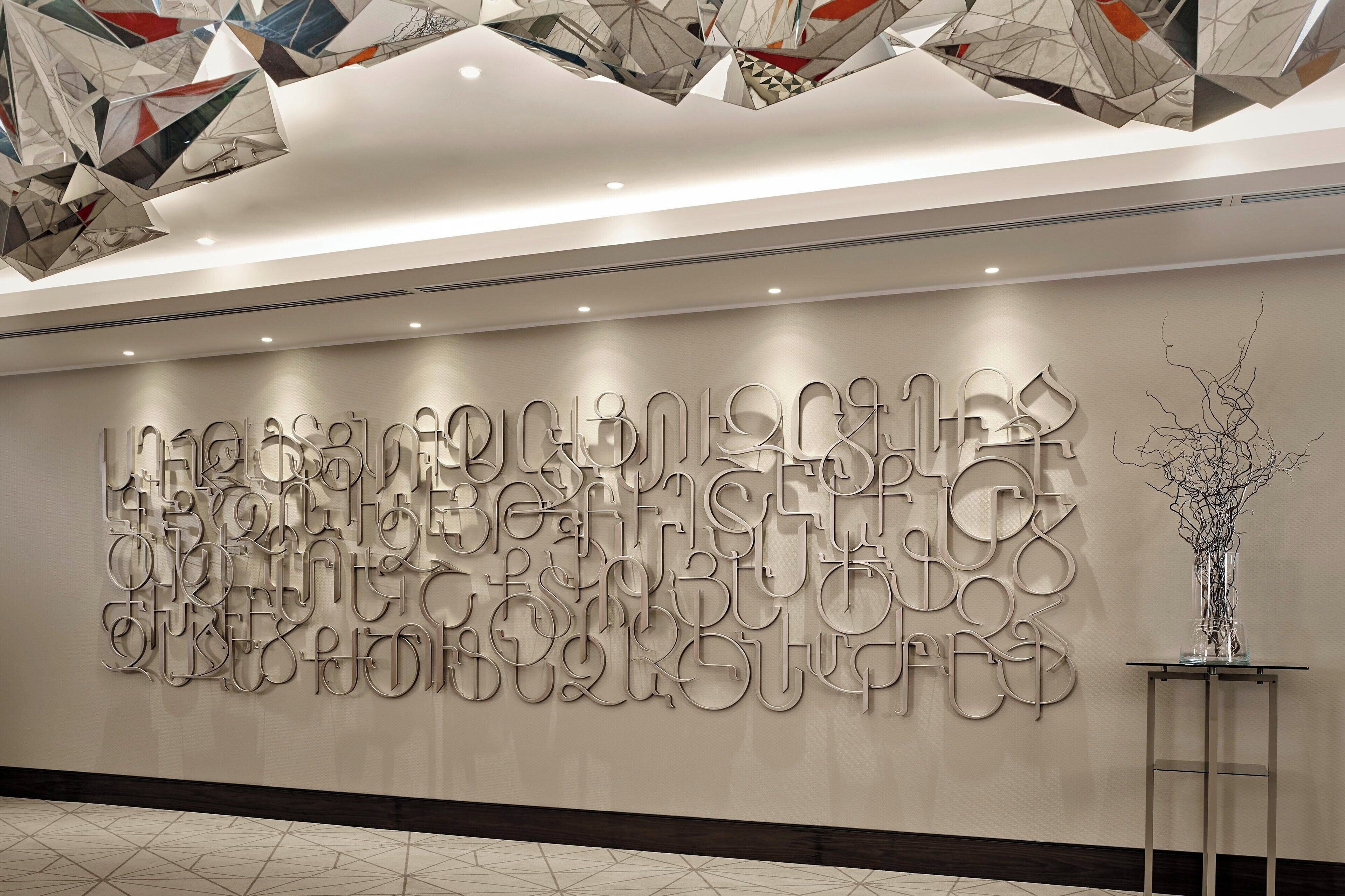 A modern interior with a geometric wall art installation and a minimalist vase on a table.