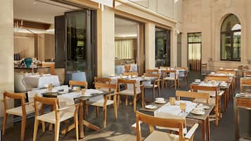 Un restaurante con terraza, mesas cubiertas con manteles blancos y sillas de madera.
