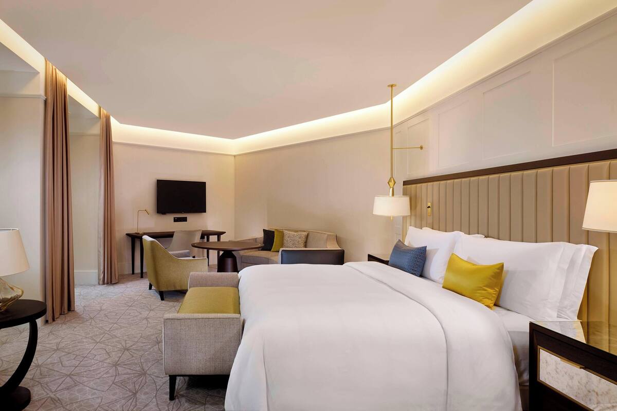 A hotel room with a large bed, a desk, a chair, and a television.