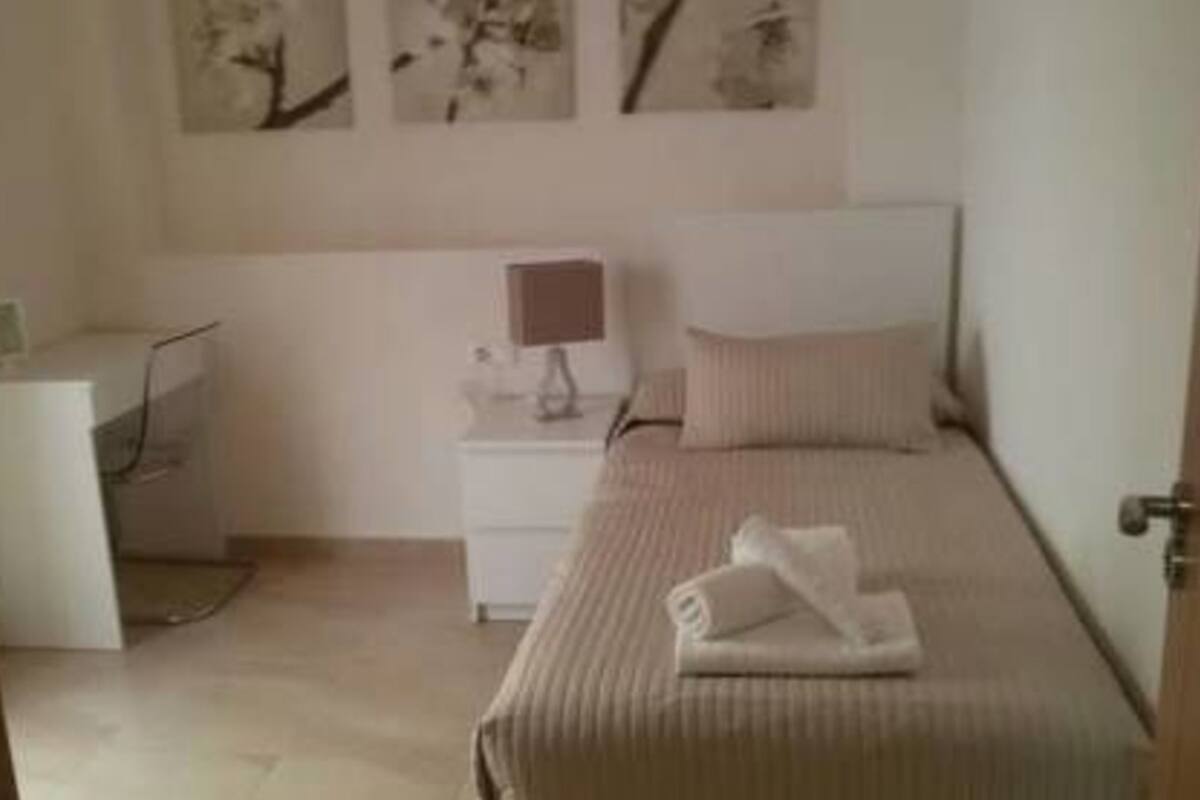 A bedroom with a bed, a nightstand, a lamp, and wall art.