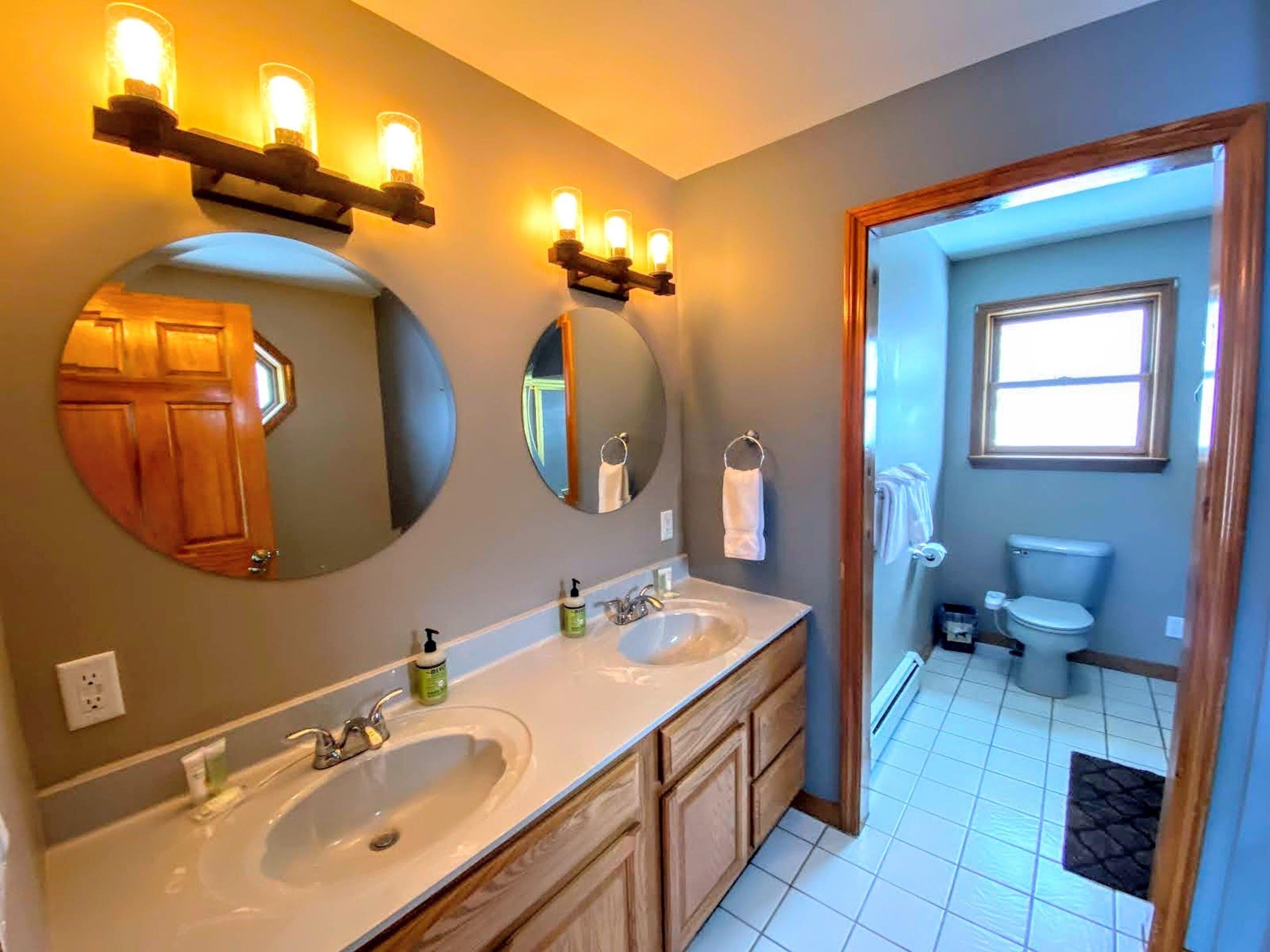 Une salle de bain avec deux lavabos, un miroir et des toilettes.