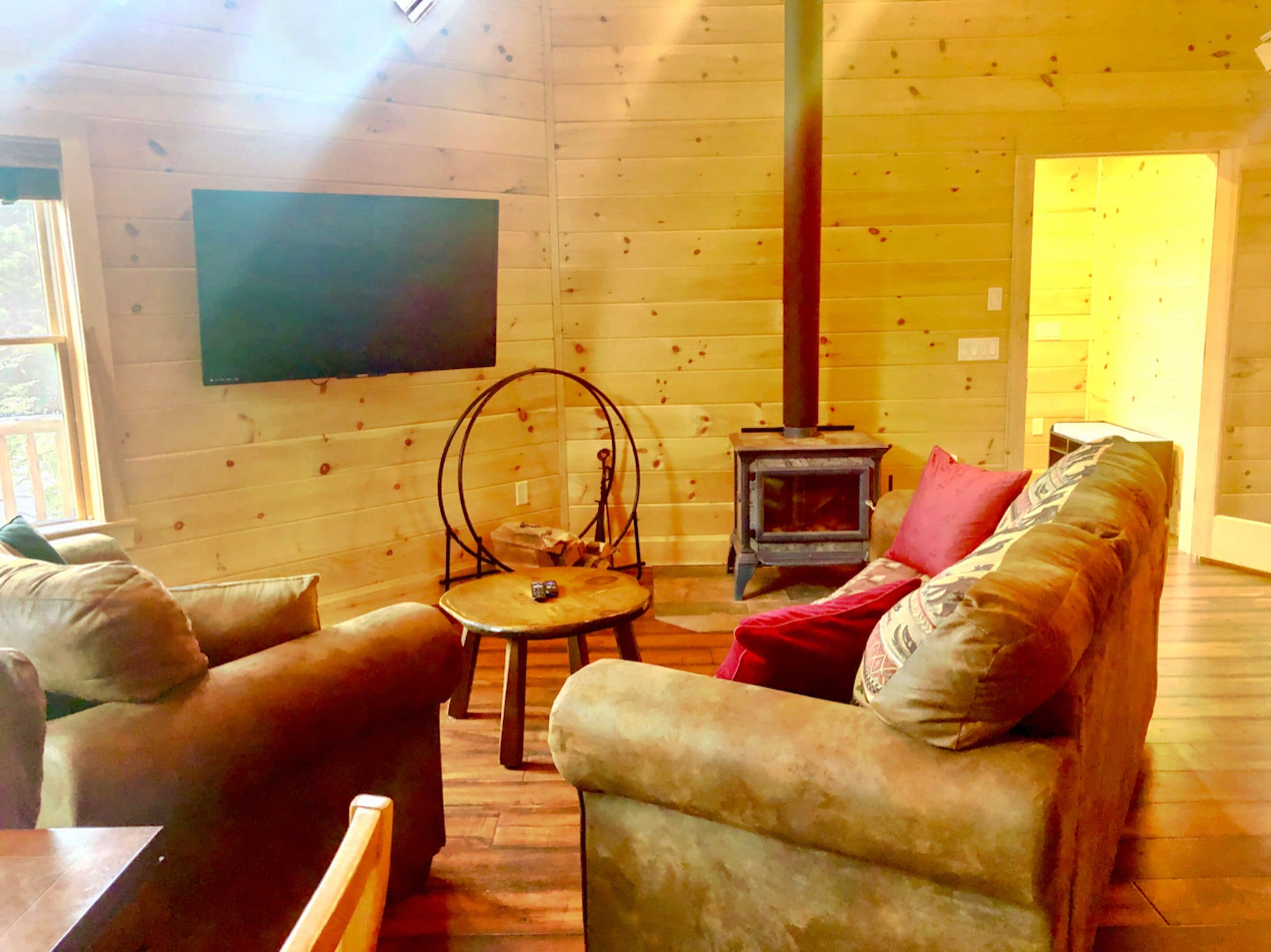 A cozy cabin interior with a wooden interior, a fireplace, a sofa, and a television.