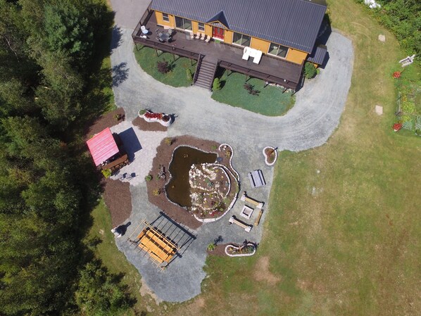 An aerial view of a two-story house with a deck, a small pond, and a fenced area with a wooden structure. - Moose Lodge and Cabins by Bretton Woods Vacations (Bretton Woods)