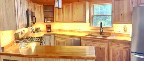 A wooden cabin kitchen with a central island, a stove, a sink, and a refrigerator.