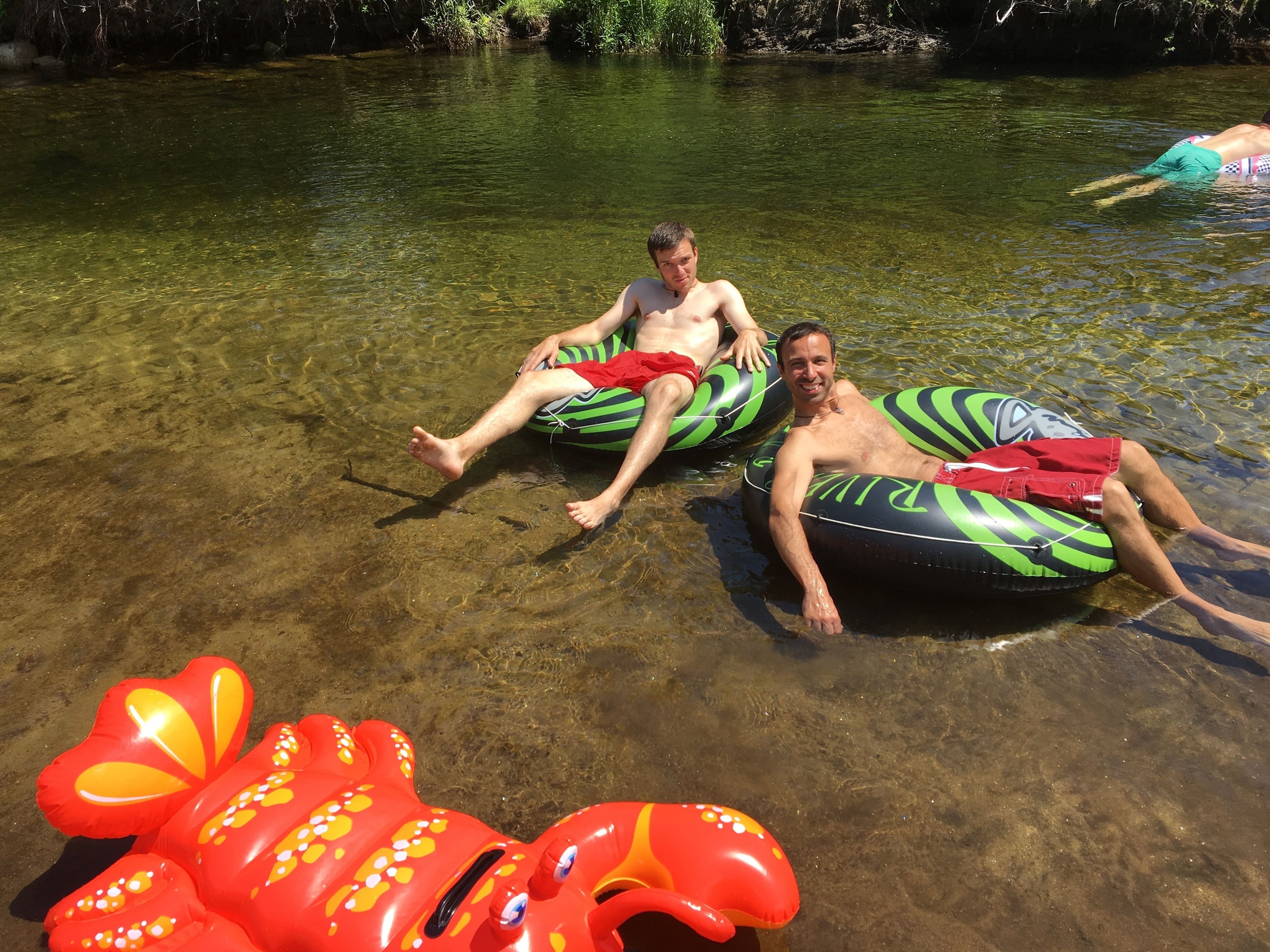 Deux personnes dans une rivière, portant des bouées gonflables.