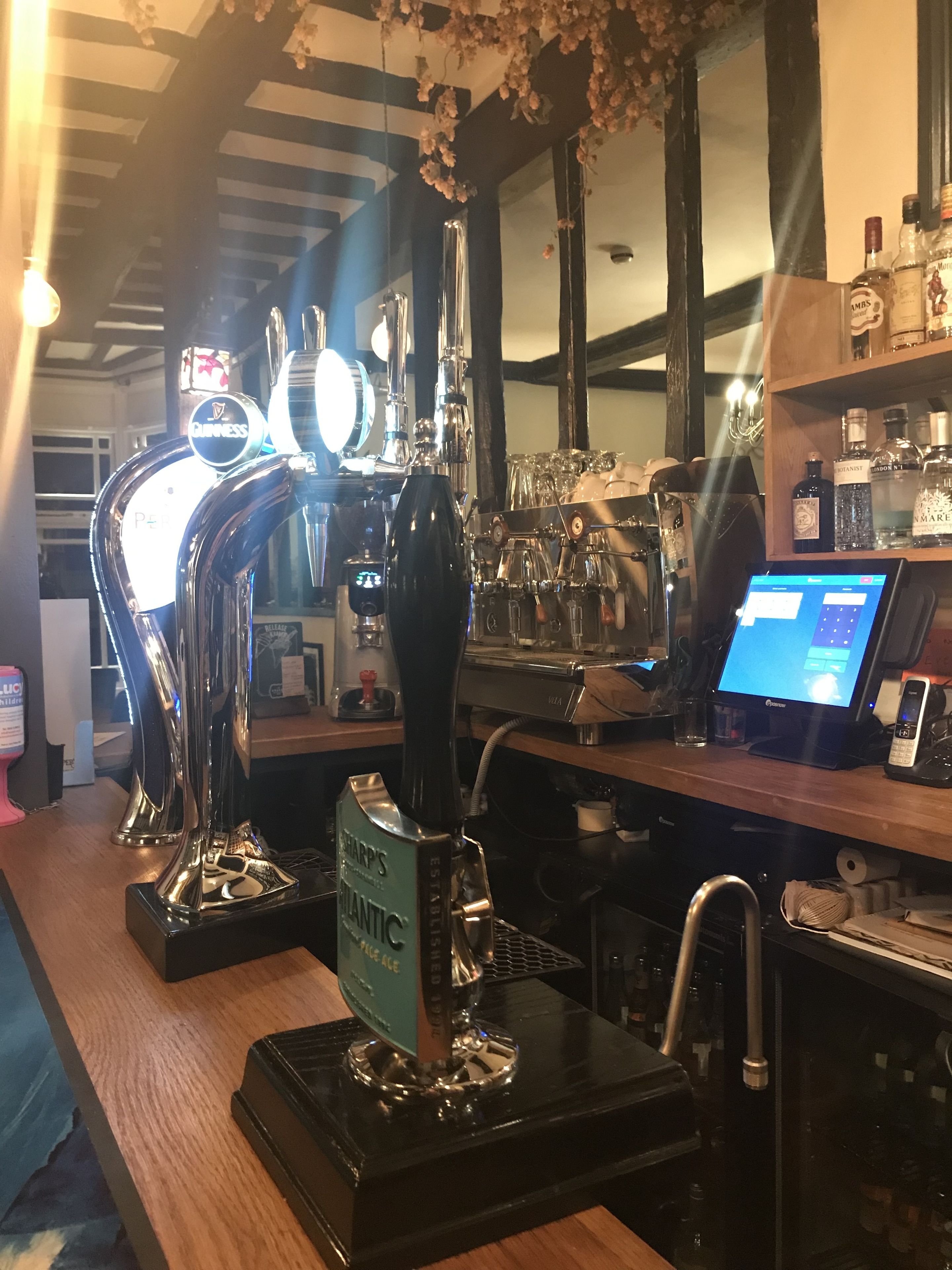 Un bar con una grifo etiquetado 'SHARP'S ATLANTIC' y una pantalla digital mostrando un menú.